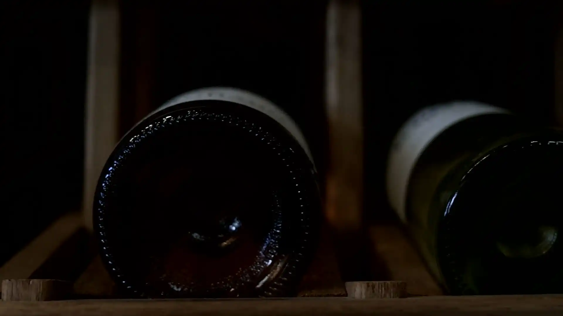 Bottles resting in a cellar, then sparkling wine rising in a flute