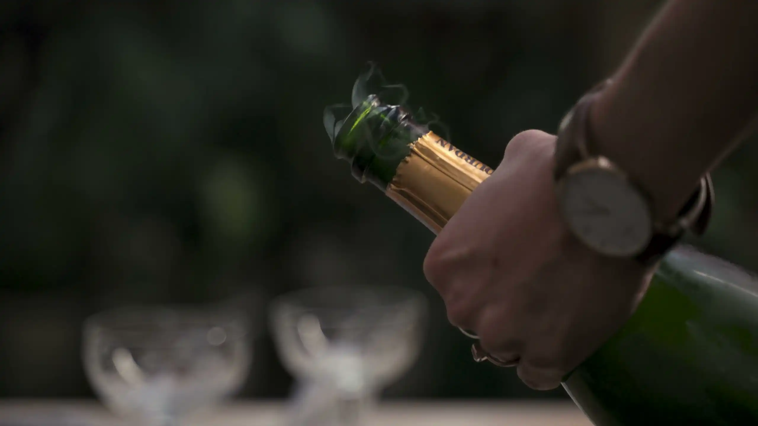 A hand easing the cork out of a sparkling wine bottle
