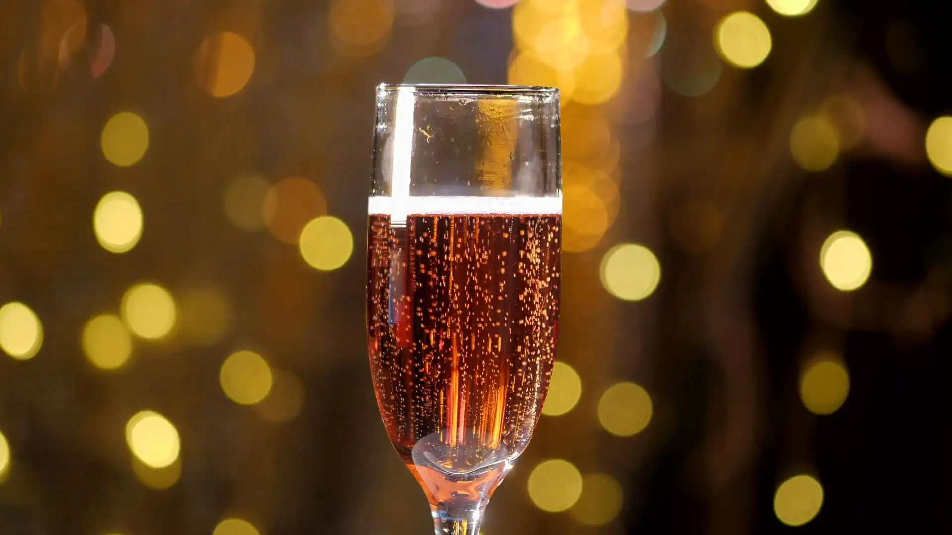A flute of Ember Hill rosé, bubbles rising, against warm cellar lights