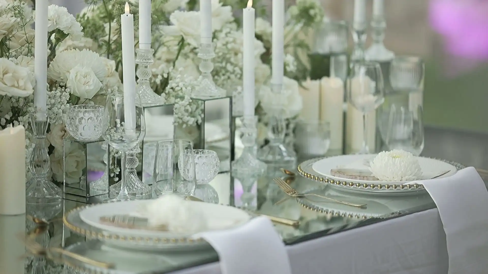 Candles, crystal glasses and white flowers on a set table