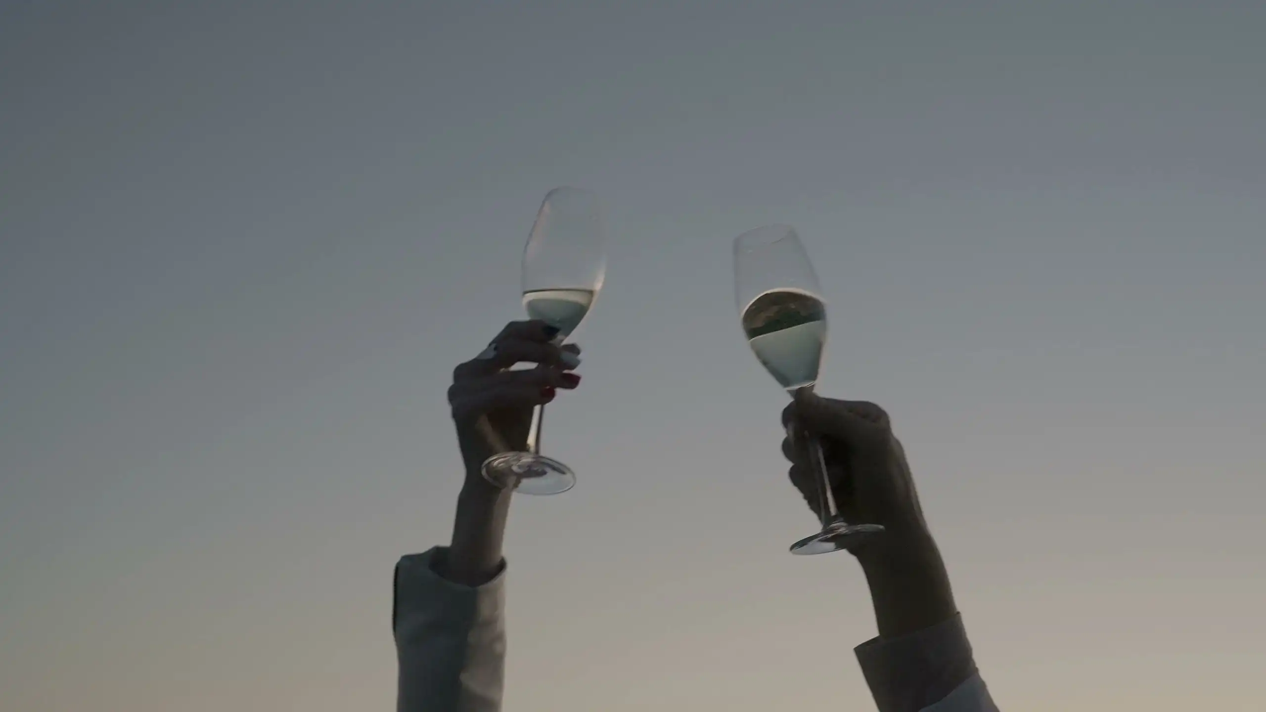 Glasses of sparkling wine raised together at dusk