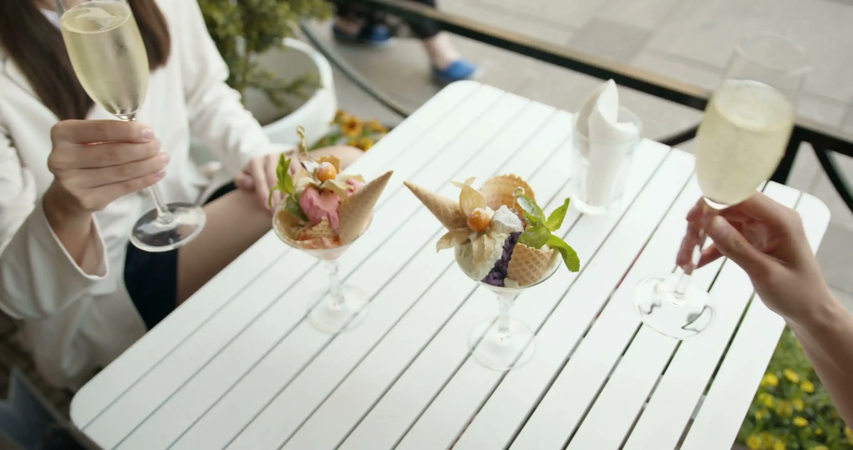 Glasses of sparkling wine beside plated desserts on a white table