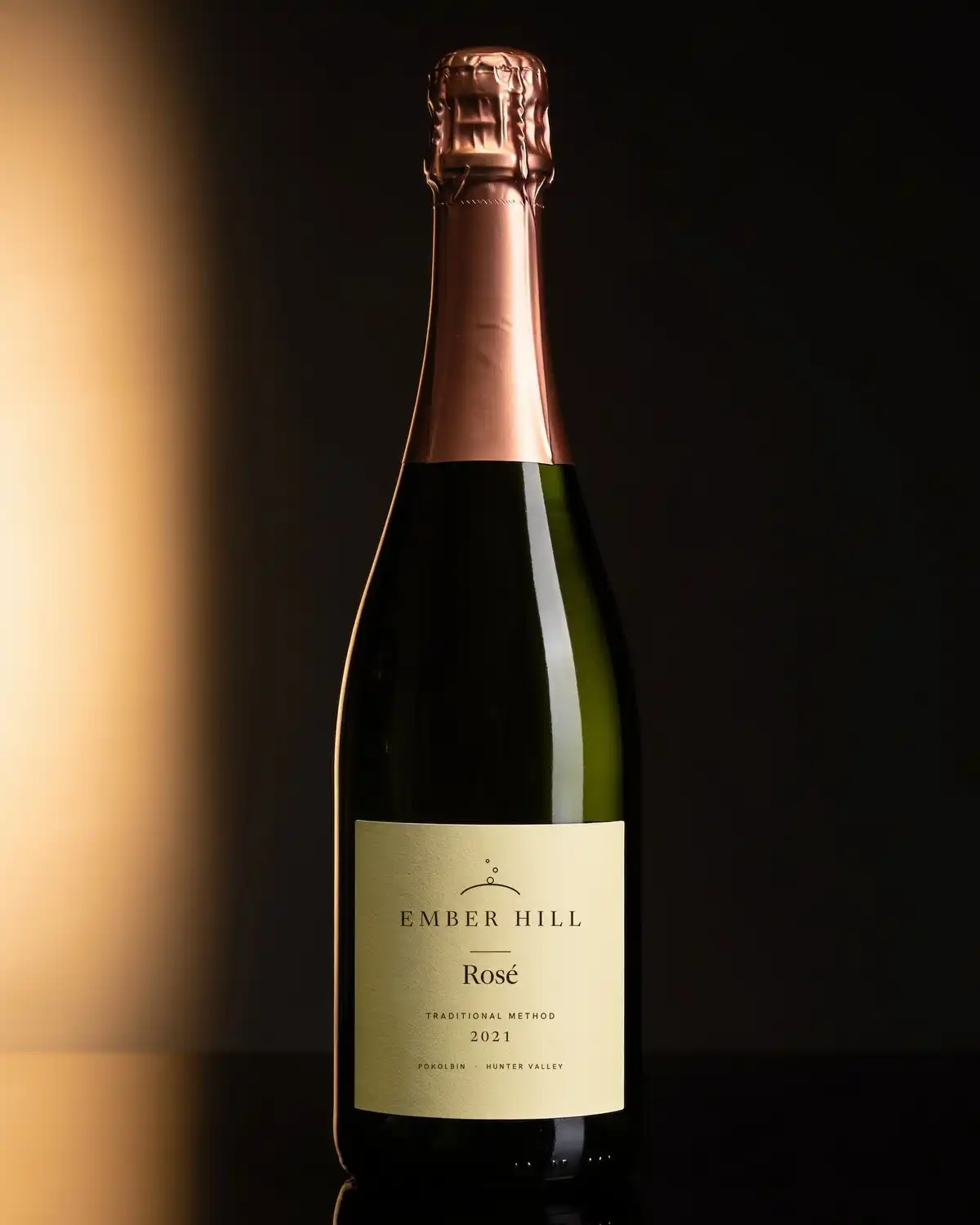 A bottle of Ember Hill Rosé with a cream label on a dark table